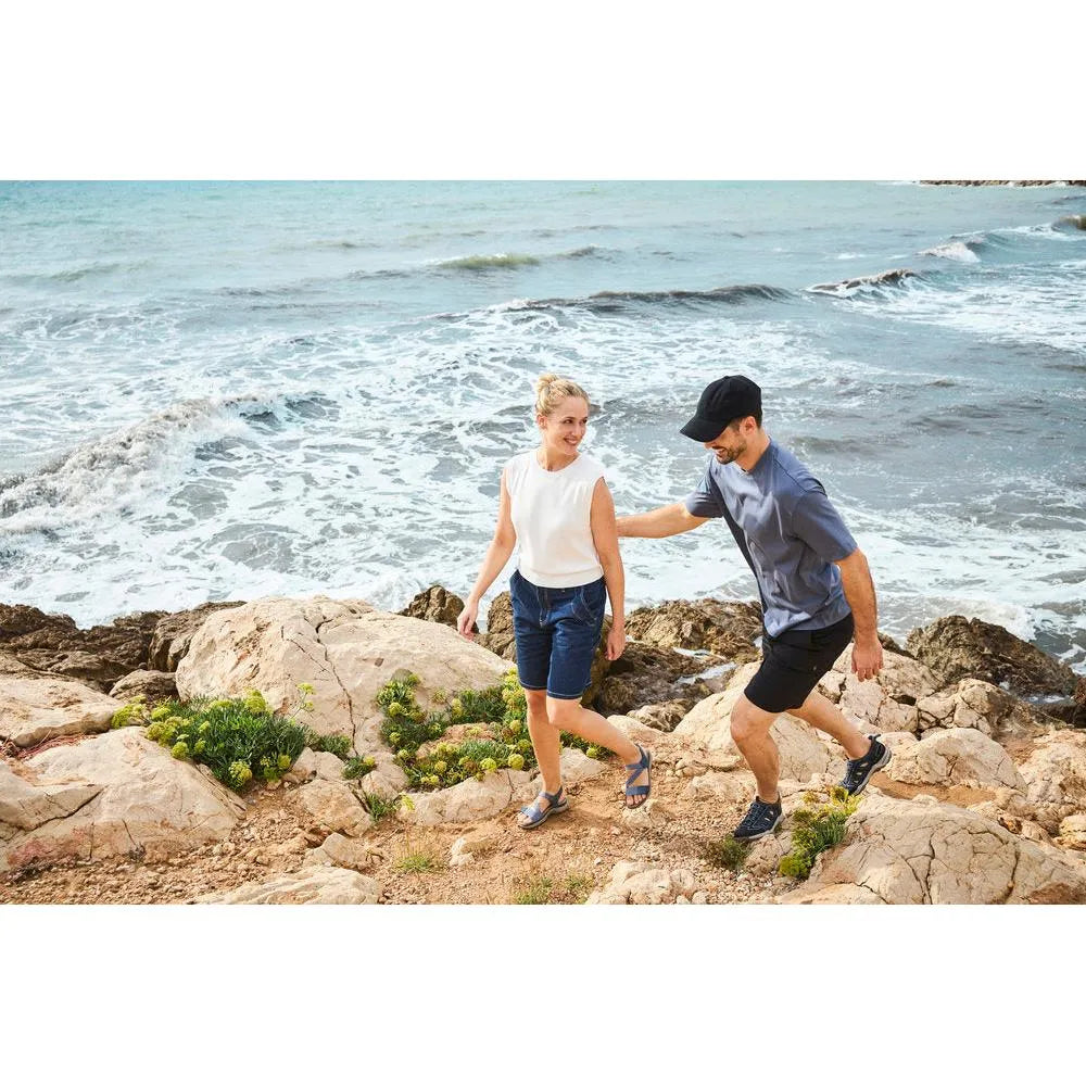 Rieker 64870-14 ladies blue Touch fastening sandals on a rocky beach with a woman and man by the sea.