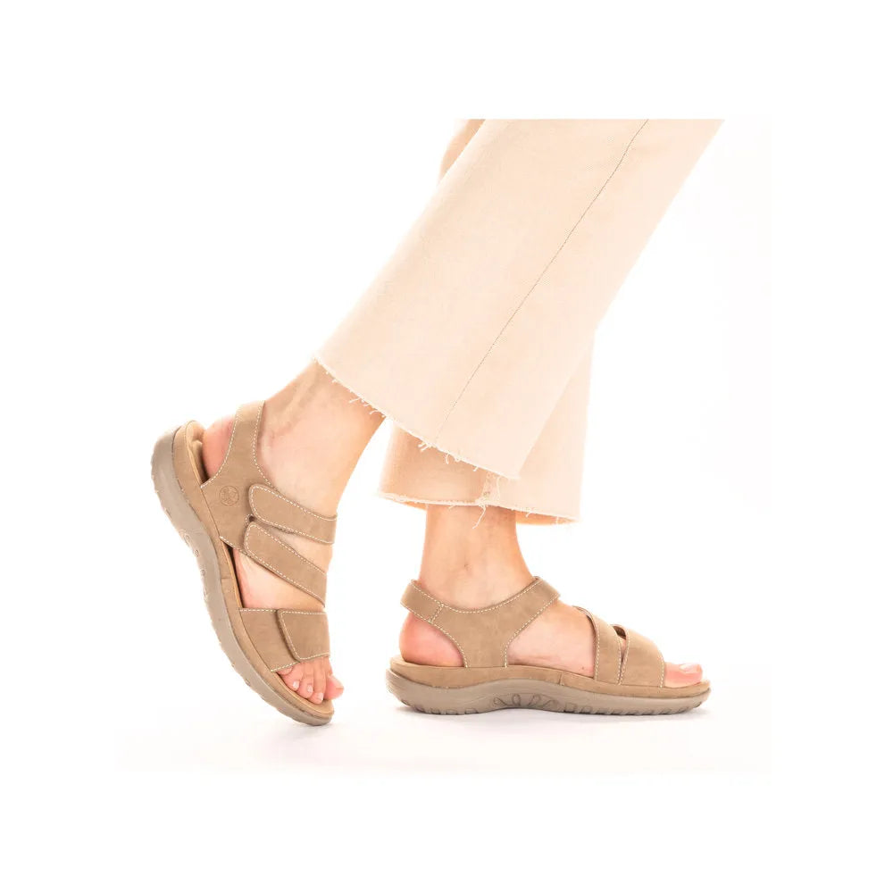 Rieker 64870-62 beige/white touch fastening sandals with cushioned soles and open-toe design, worn with light-colored cropped pants.