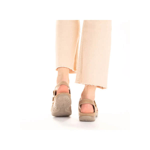 Beige touch fastenings sandals with open toes, chunky soles, and adjustable straps worn by a person in light-colored frayed trousers.