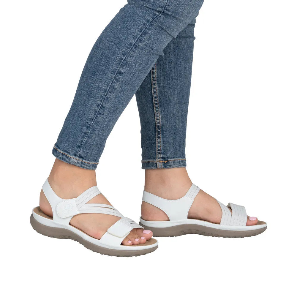 White touch fastening sandals with wide straps, open toes, and cushioned soles, worn with blue jeans.