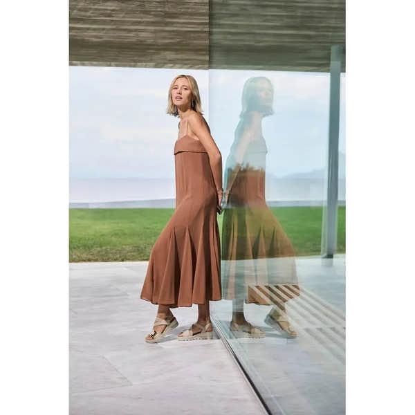 Rieker 67410-62 beige touch fastening women's sandals with chunky heel, worn by a woman in a brown maxi dress, outside by a glass wall.