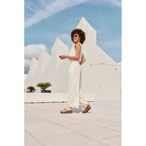 Rieker 68172-60 beige touch fastening sandals worn by woman in white outfit outdoors with modern white architectural background.