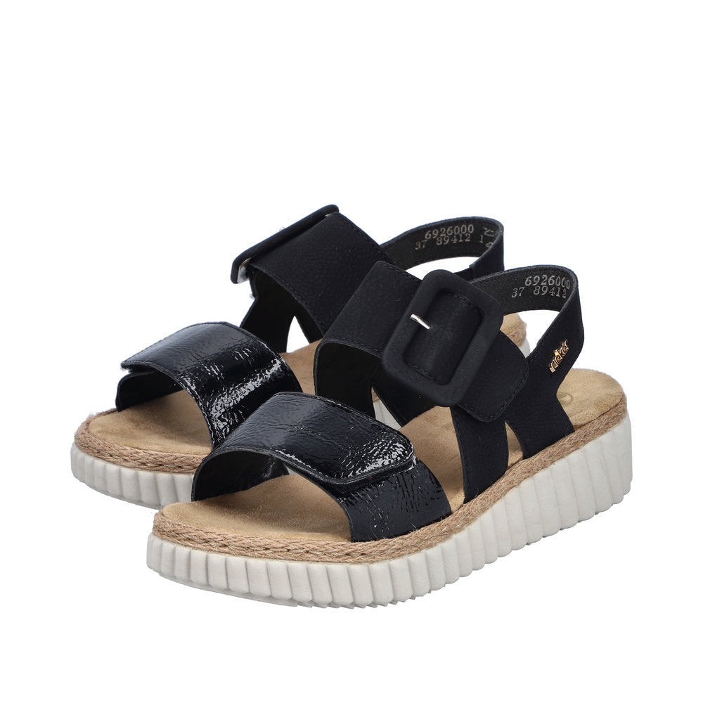 Rieker 69260-00 women's wide black buckle sandals with glossy straps, cushioned footbed, and chunky white outsole.
