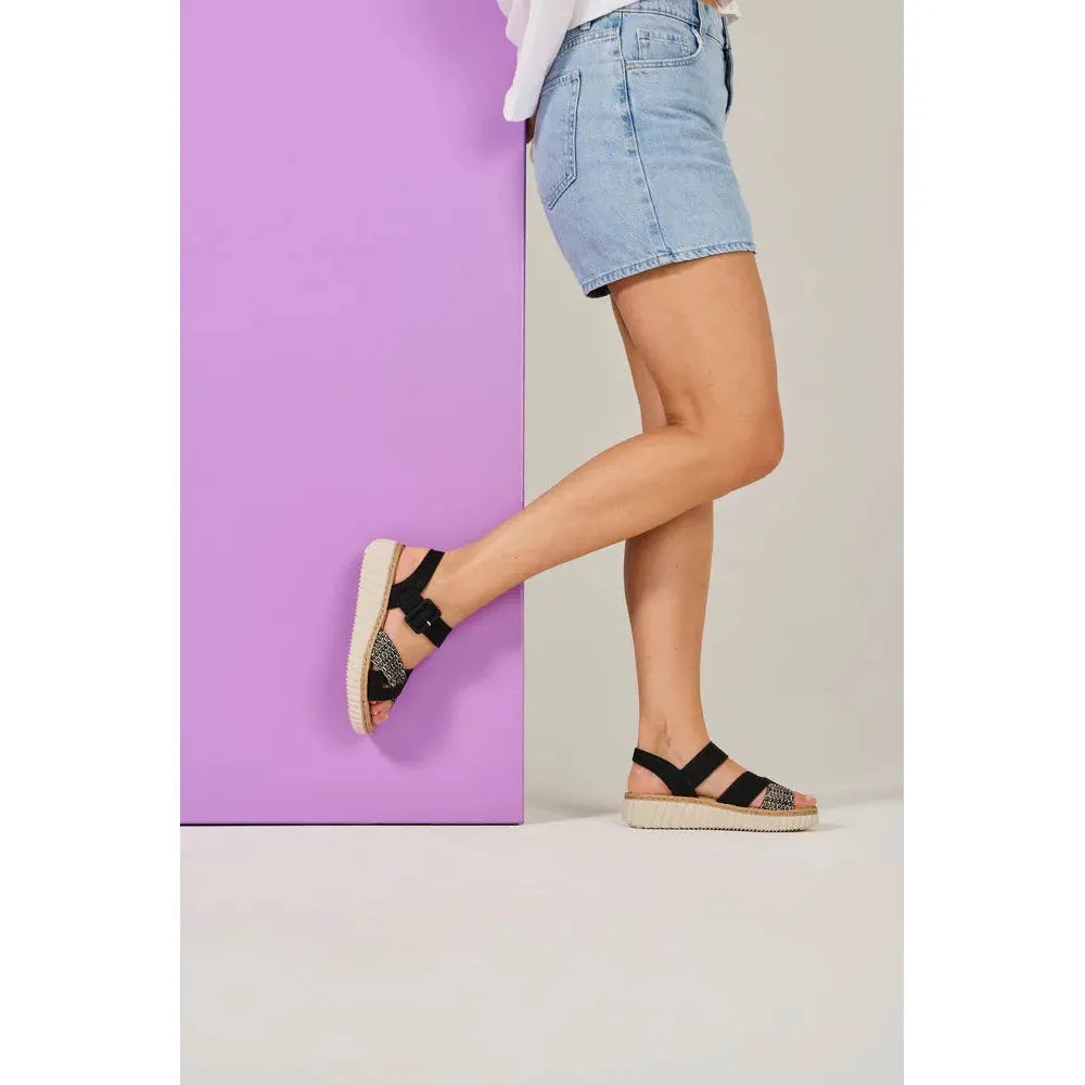 Rieker 69269-00 women's wide black touch fastening sandals with decorative details, worn with denim shorts.