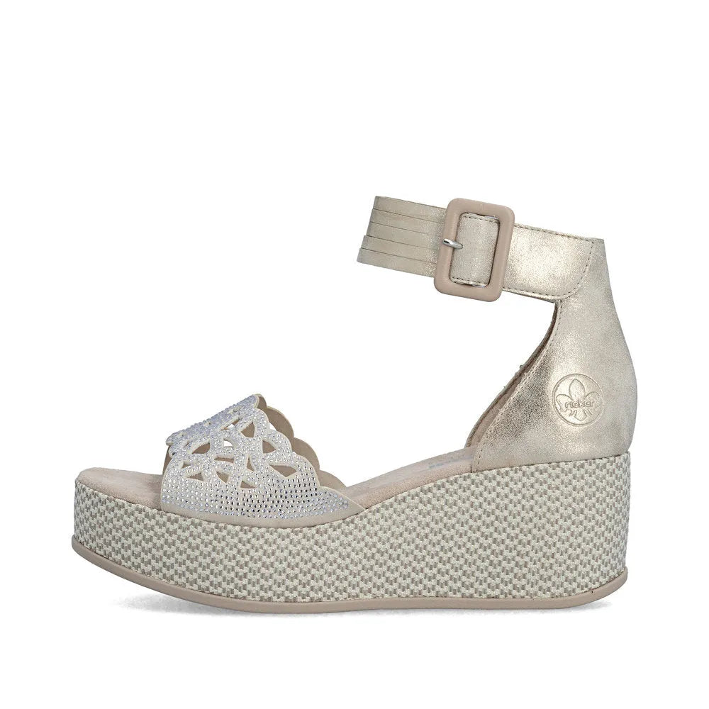 Rieker 69457-60 beige women's wedge sandals with ankle strap, buckle closure, decorative front detail, and textured platform sole.