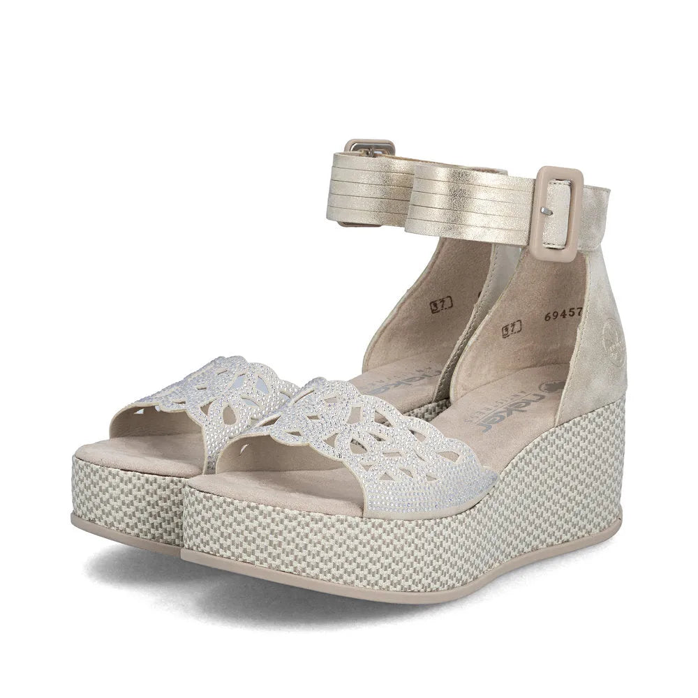 Rieker 69457-60 women's beige buckle wedge sandals with decorative cut-out strap and textured platform sole.