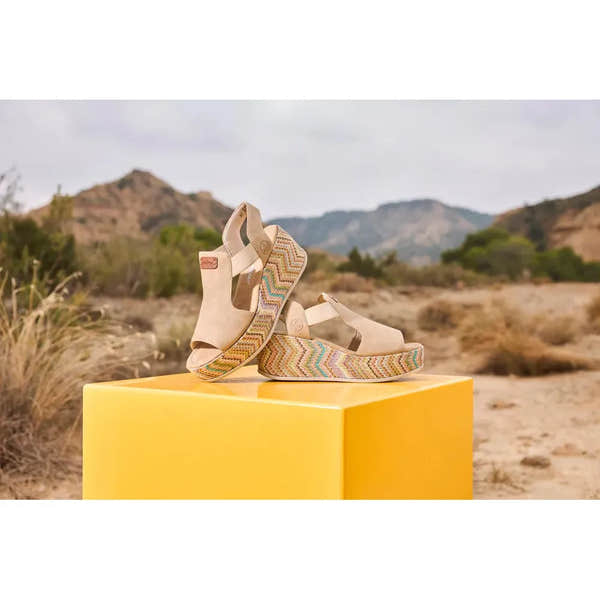 Rieker 69472-60 women's beige elasticated sandals with colorful patterned platform soles, outdoor desert landscape backdrop.