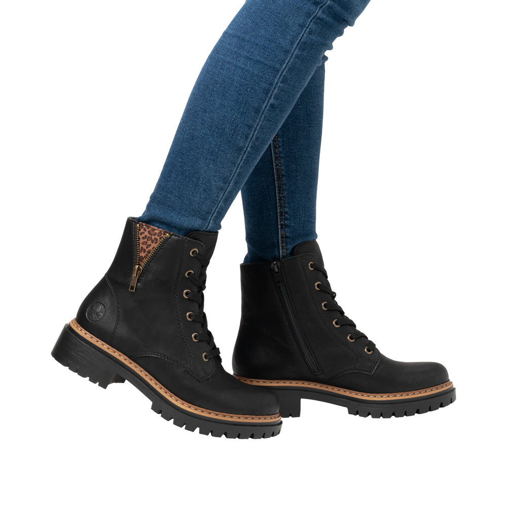 Rieker 72617-00 women's black ankle boots with lace-up front, zip side, and animal print detail on collar.
