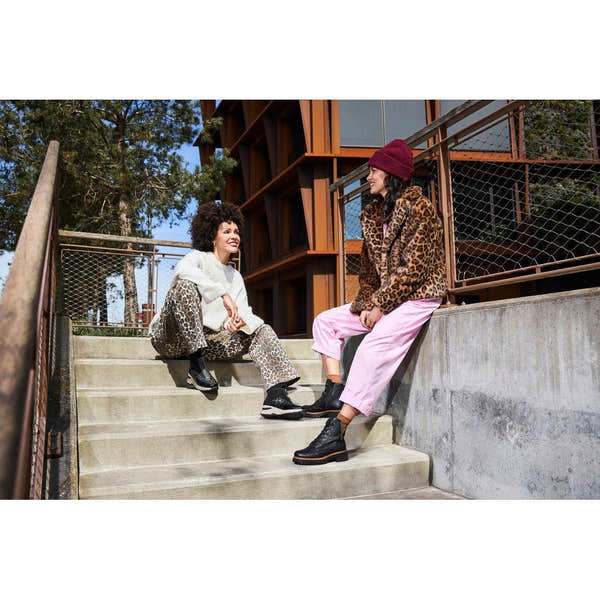 Rieker 72617-00 women's black zip and lace ankle boots with chunky sole, worn by two women in trendy animal print and casual outfits.
