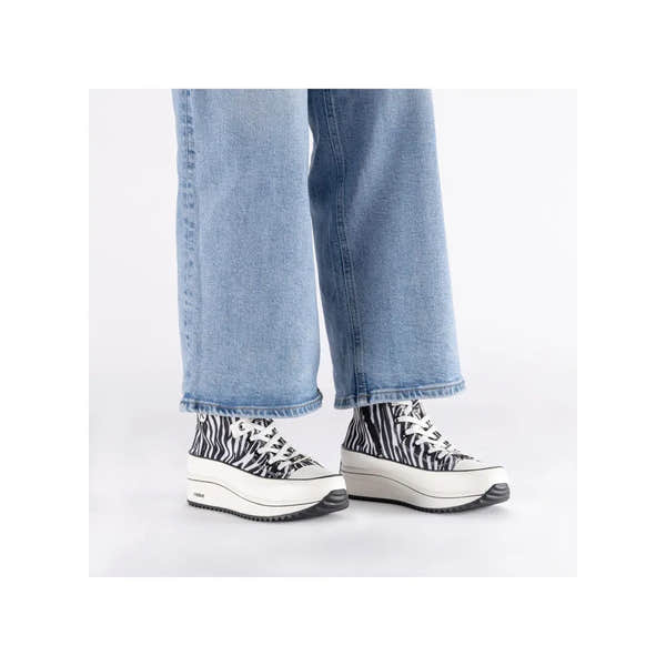 Zebra print vegan ankle boots with white platform soles, laces, and side zip, paired with light blue jeans.