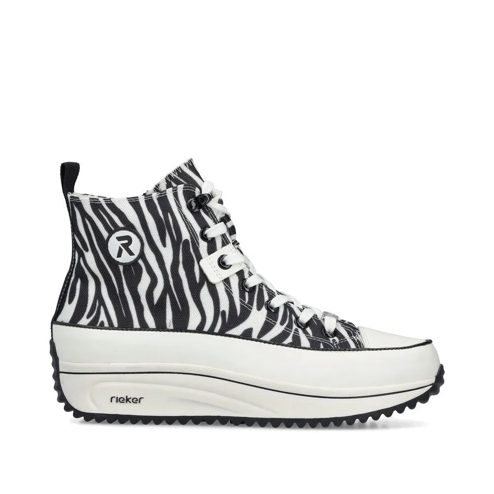 Black and white zebra-patterned vegan ankle boots with lace and zip closure, chunky sole, and Rieker branding.