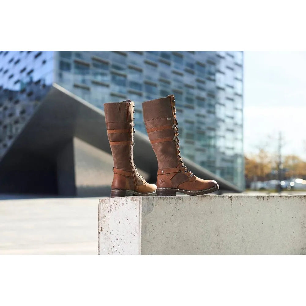 Rieker 94732-25 Ladies Brown Water-Resistant Knee-High Boots with Zipper and Lace Detail in an outdoor urban setting.