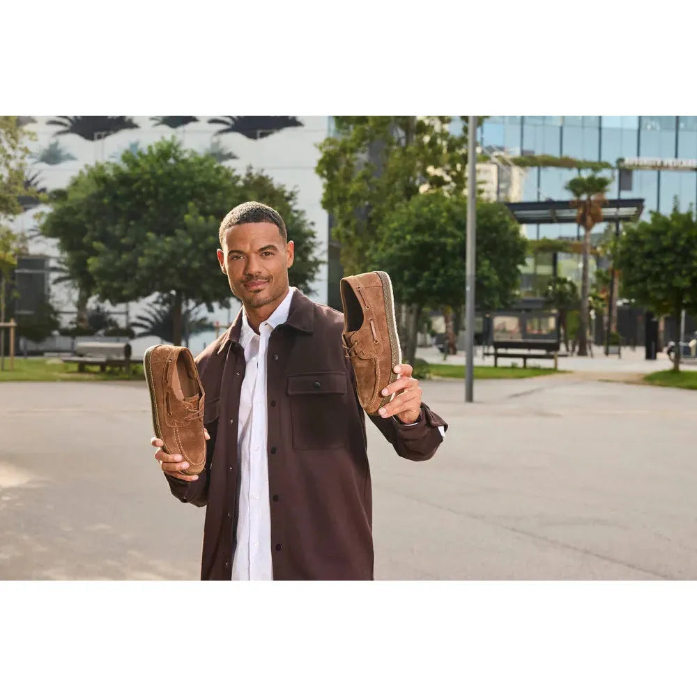 Man holding Rieker B5220-22 men's wide fit brown suede lace-up shoes outdoors.