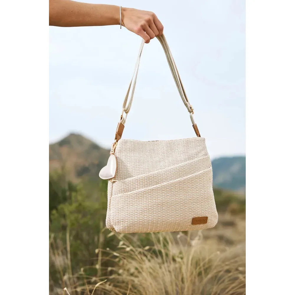 Rieker H1004-62 Pale Gold Handbag with adjustable strap, woven texture, and front pocket, outdoor setting.