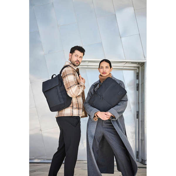 Rieker H5000-00 black business bags worn by stylish man and woman outside modern building.