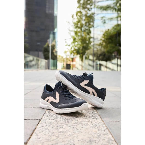 Black and beige elasticated slip-on shoes with white soles, casual style, outdoor urban setting.