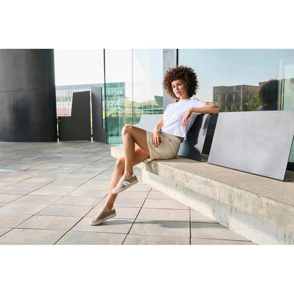 Woman wearing beige suede Rieker L5903-20 zip and lace casual shoes, sitting on a bench outside.