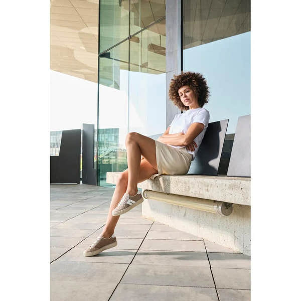 Rieker L5903-20 ladies camel suede shoes with zip and lace-up styling, worn by a woman sitting outdoors by a modern building.