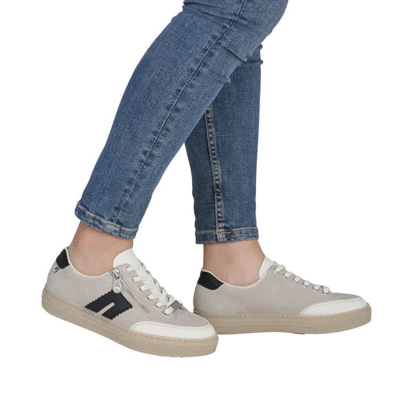 Rieker L5903-40 women's off-white suede sneakers with zip, lace-up design, and beige soles, paired with blue jeans.