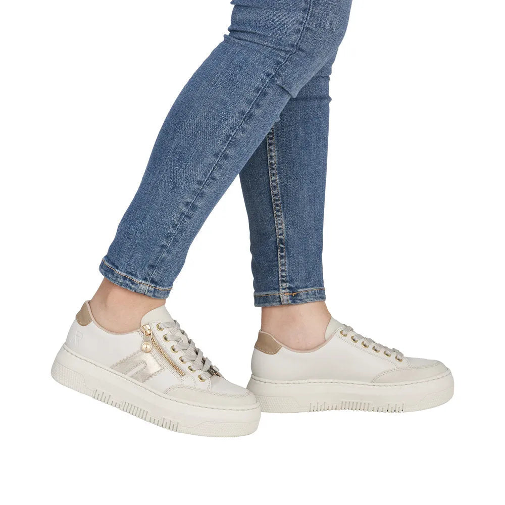 White leather trainers with zip and lace details, beige accents, and chunky soles worn with blue jeans.