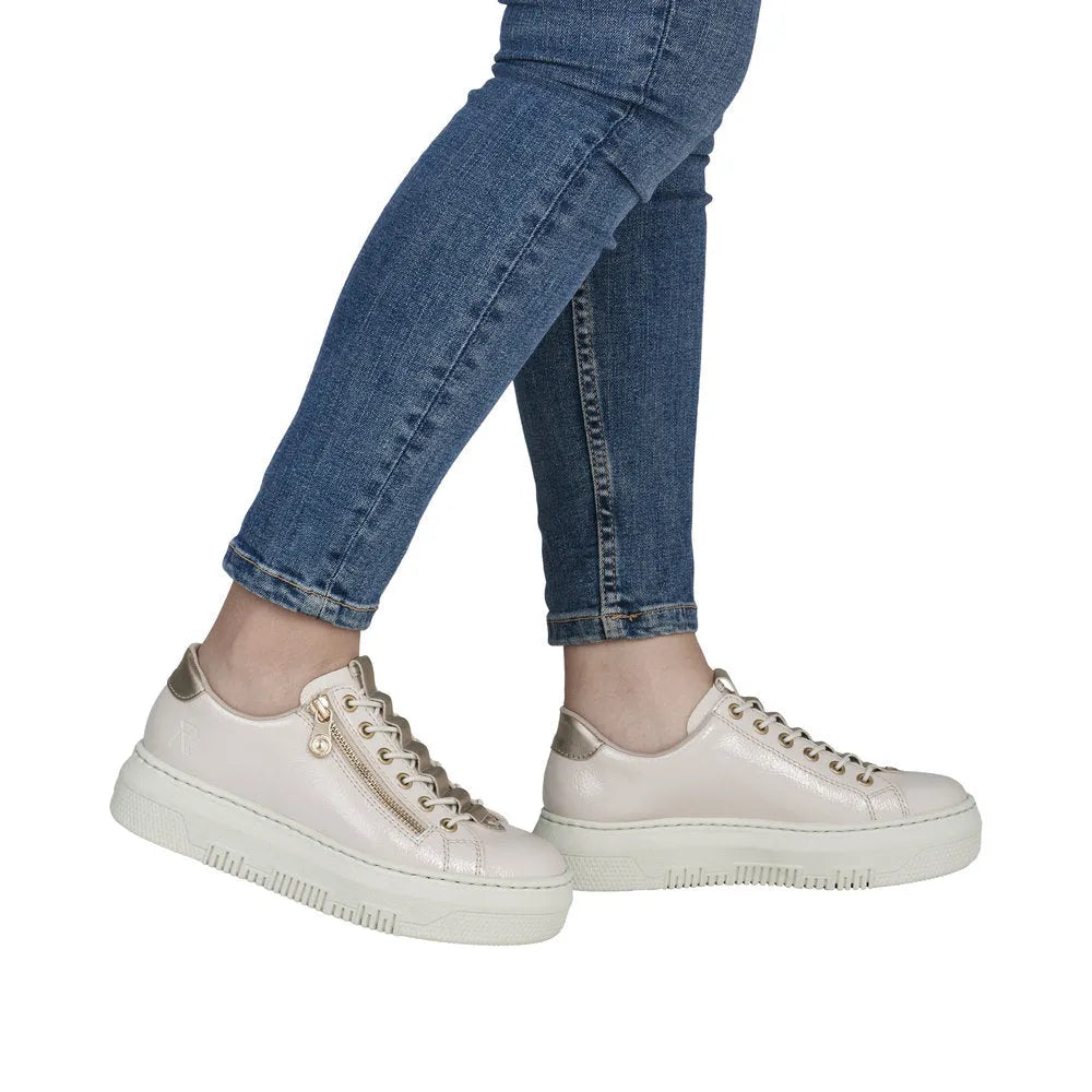 Rieker M1953-80 women's off-white patent trainers with side zipper, metallic accents, and chunky white sole.