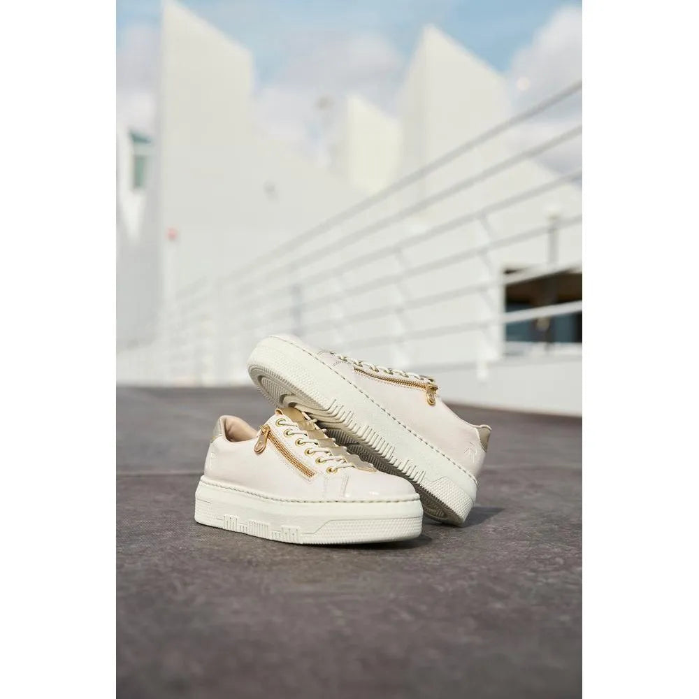 Rieker M1953-80 ladies off-white patent trainers with side zipper and chunky sole, set outdoors against a white modern building.
