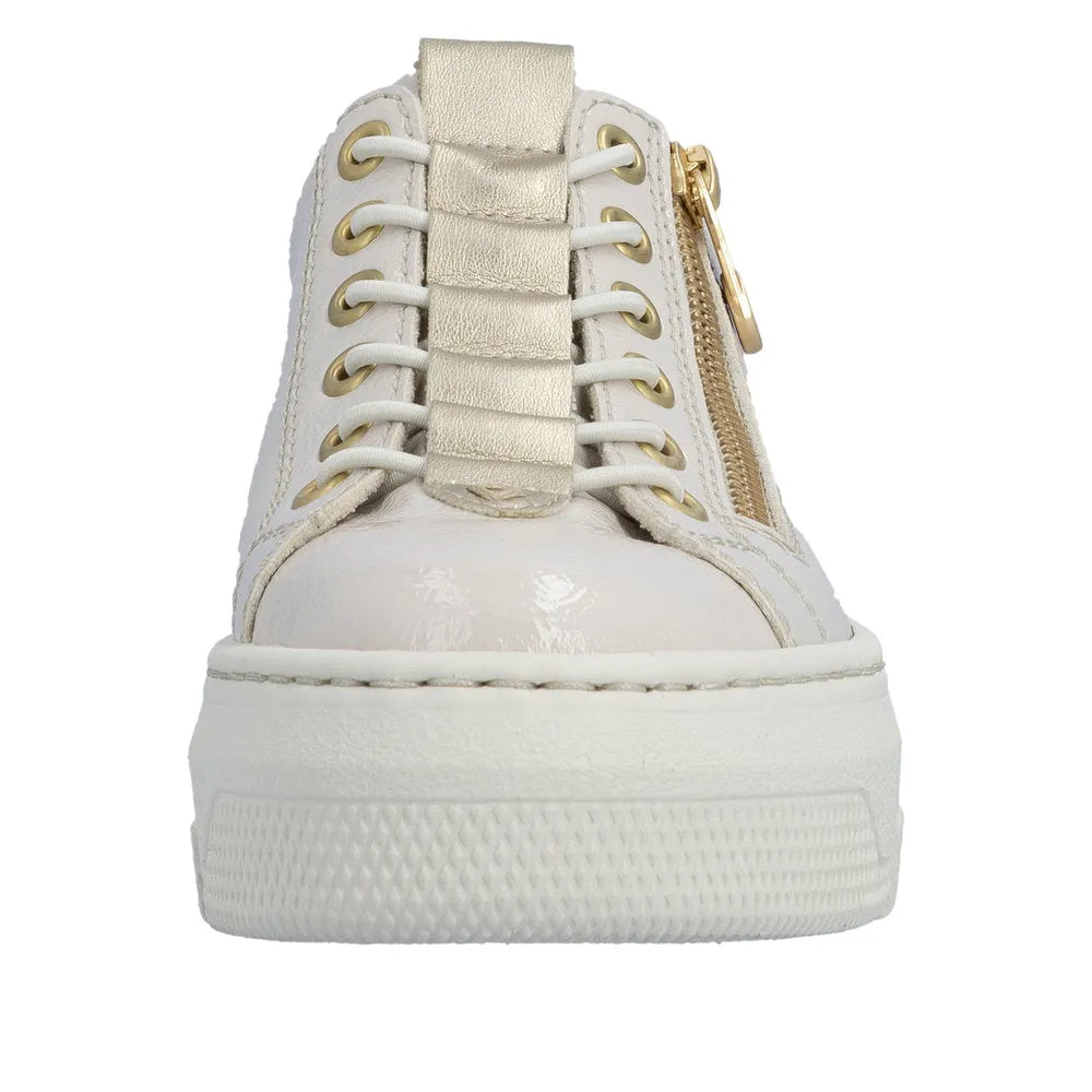 Off-white patent lace-up trainer with side zipper, gold accents, chunky sole, and metallic gold strap detail.