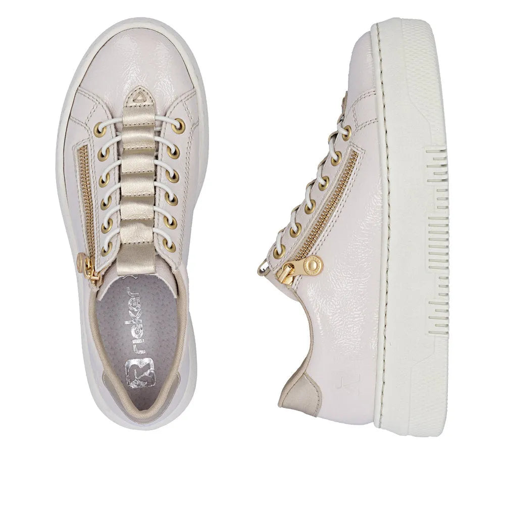 Off-white patent trainers with side gold zipper, lace-up front, and textured sole, featuring gold eyelets and beige accents.