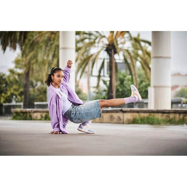 Rieker M5520-91 ladies multi-zip and lace trainers, casual sneakers with pastel accents, worn by a woman performing a dance pose outdoor.