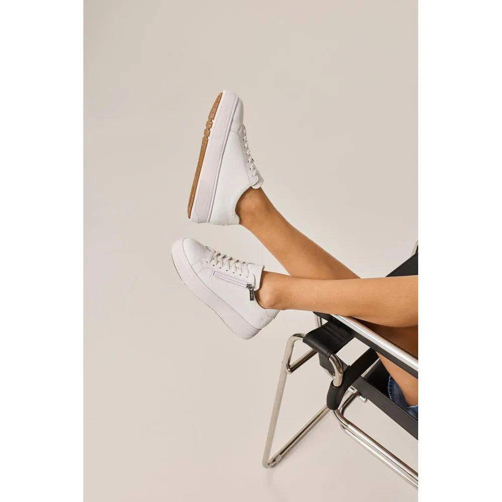 White leather ladies' shoes with zipper and laces, chunky soles, and side zippers, on a person's feet.