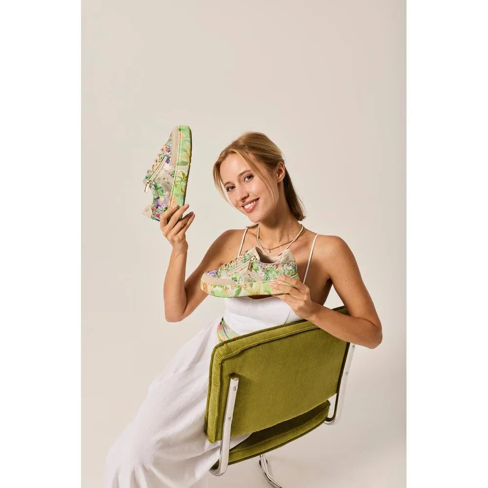 Woman holding colorful multi-color trainers with side zips, featuring mixed materials and vibrant floral design.