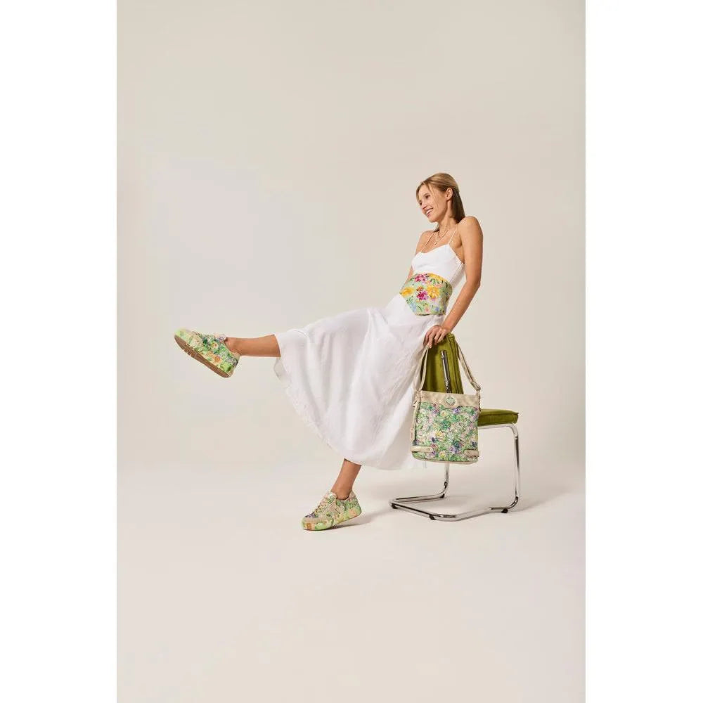 Ladies white dress with colorful floral side zip trainers, holding a floral bag, sitting on a chair.