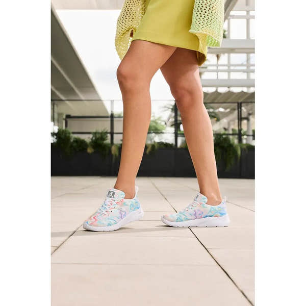 Rieker M8500-90 vegan lace-up trainers for women, multicolored textile with white soles, worn by a person in a bright outdoor setting.