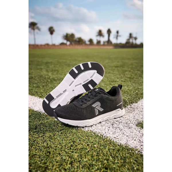 Rieker M9006-00 women's black textile lace-up trainers on a sports field with a white sole and logo detail.