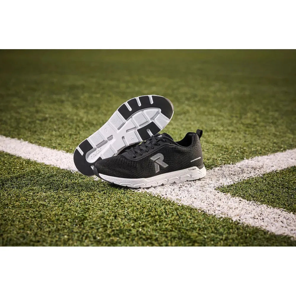 Rieker M9006-00 women's wide black textile lace-up trainers on grass with white sole and logo details.
