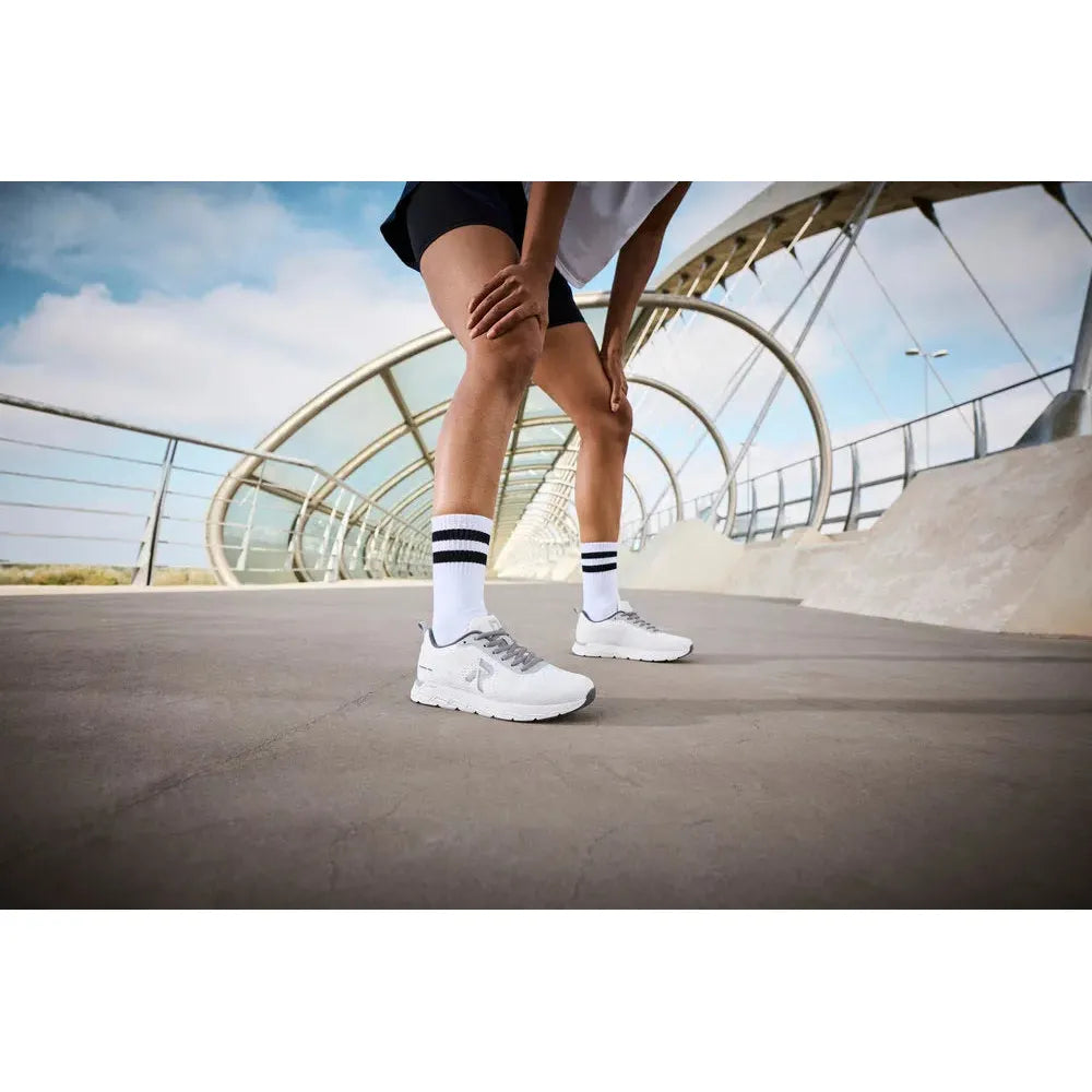 Rieker M9006-80 ladies wide white and grey textile lace-up trainers on a modern outdoor walkway.