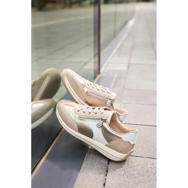 Rieker N1103-90 women's wide white and champagne sneakers with zipper and lace-up design, placed on sidewalk near glass window.