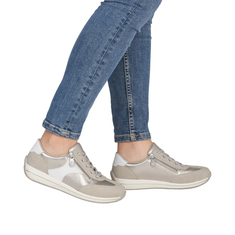 Rieker N1103-90 women's wide fit white and champagne sneakers with laces and side zippers, featuring mixed materials.