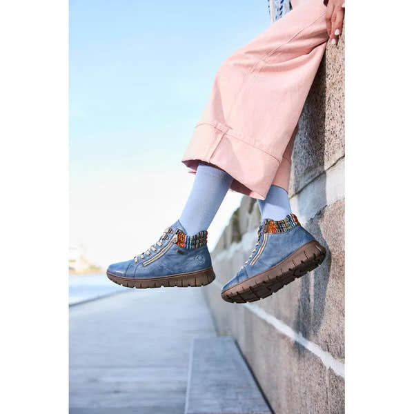Rieker N1305-14 ladies blue leather ankle boots with zip and lace details, paired with light blue socks and pink pants.