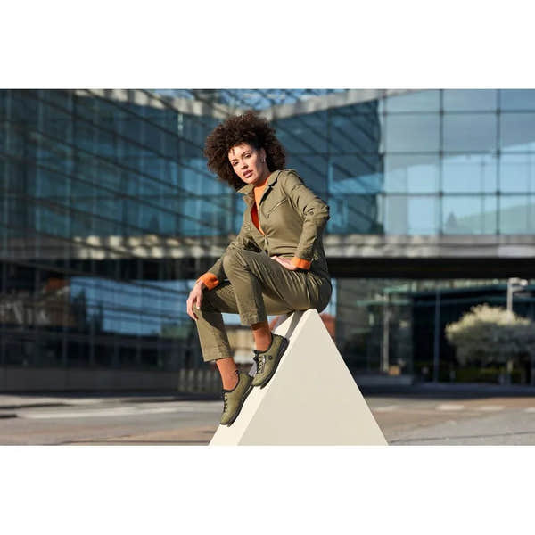 Rieker N3267-54 women's green slip-on shoes, outdoor setting with woman sitting on a white geometric structure, casual sporty design.
