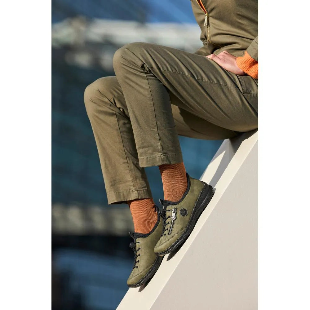 Rieker N3267-54 ladies green Slip-On shoes with black soles, casual outdoor footwear, worn with orange socks, side view.