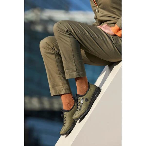 Rieker N3267-54 ladies green Slip-On shoes with black soles, casual outdoor footwear, worn with orange socks, side view.
