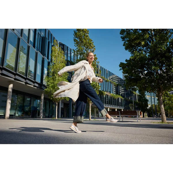 Woman wearing Rieker N4221-90 rose-metallic zip and lace shoes, walking outdoors in a cityscape.