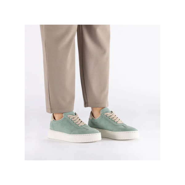 Mint suede lace-up trainers with white sole, styled with beige pants, lightweight and casual footwear.