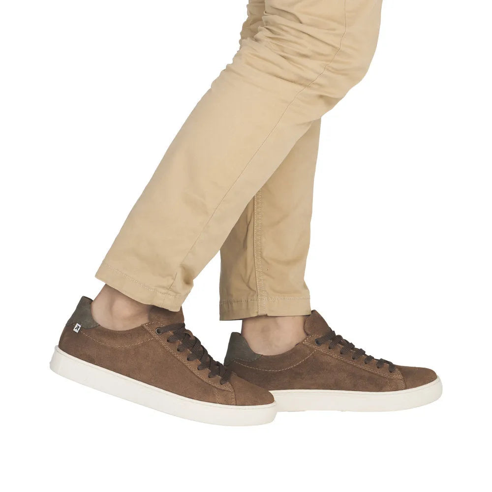 Men's brown suede lace-up shoes with white sole, styled casually over beige pants.