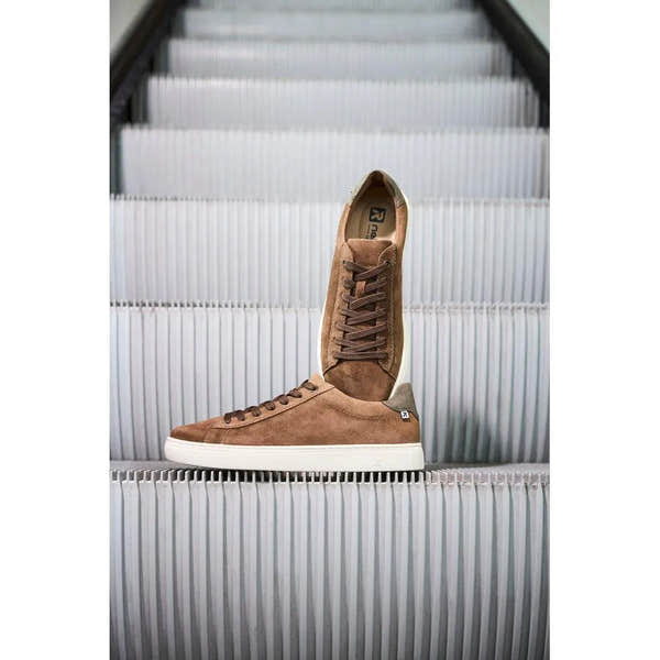 Brown suede lace-up men's shoes with white sole, high-top style, on white escalator steps.