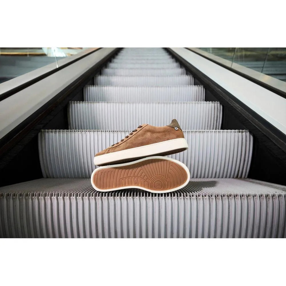 Brown suede lace-up men's shoes with white sole, displayed on an escalator.