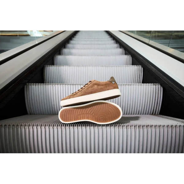 Brown suede lace-up men's shoes with white sole, displayed on an escalator.
