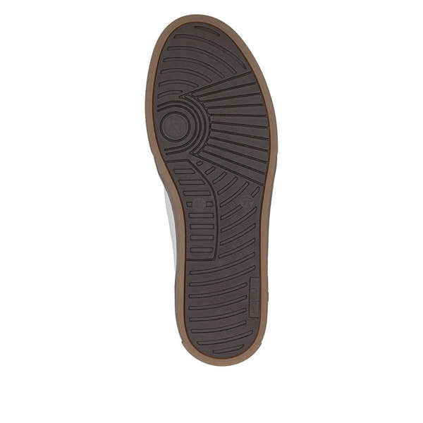 Black rubber sole with circular and linear tread patterns, brown edge, beneath white leather lace-up shoes.