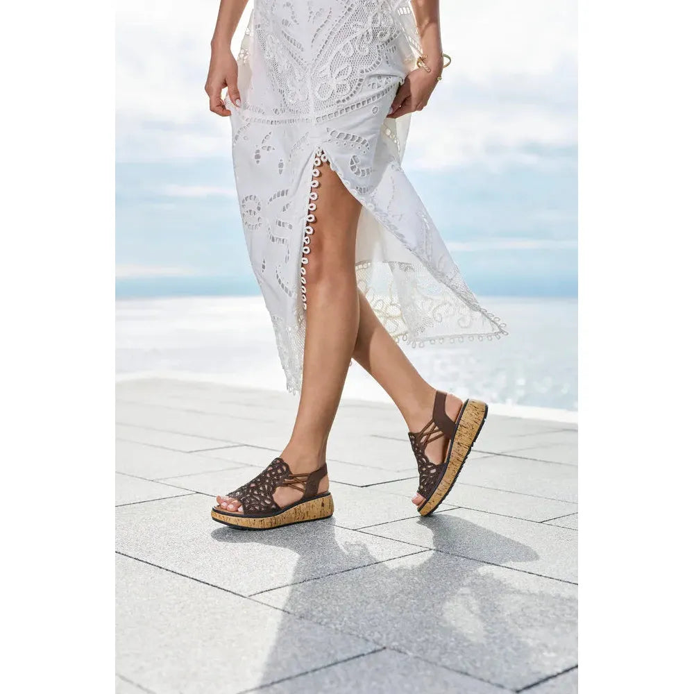 Rieker V1765-24 ladies wide fit brown elasticated sandals with open back and cork platform sole, worn by a woman outdoors.